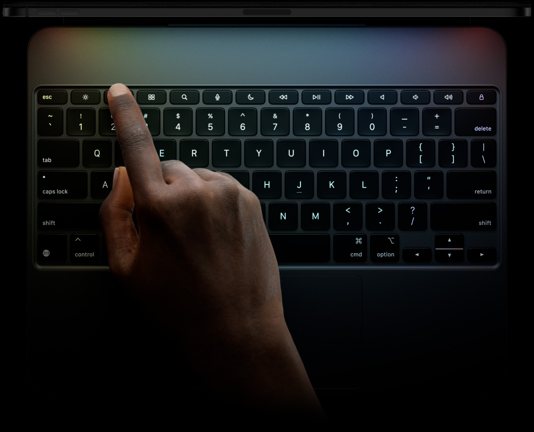 iPad Pro, Querformat, Farbe Space Schwarz, Profil am oberen Rand, befestigt am Magic Keyboard, Vorderansicht, Querformat, schwarz beleuchtete Tasten, Reihe mit Funktionstasten, Escape‑, Tab‑, Feststell‑, Umschalt‑, Steuerungs‑, Options‑, Umschalt‑, Lösch‑ und Eingabetaste, Pfeiltasten in umgekehrter T‑Anordnung, integriertes Trackpad