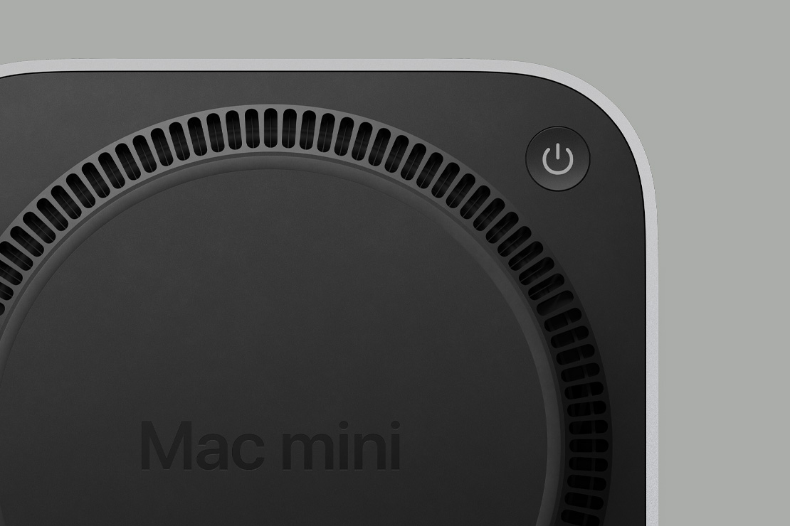 Вид на Mac mini знизу; показано чорну панель з кнопкою живлення та вентиляційні отвори по колу
