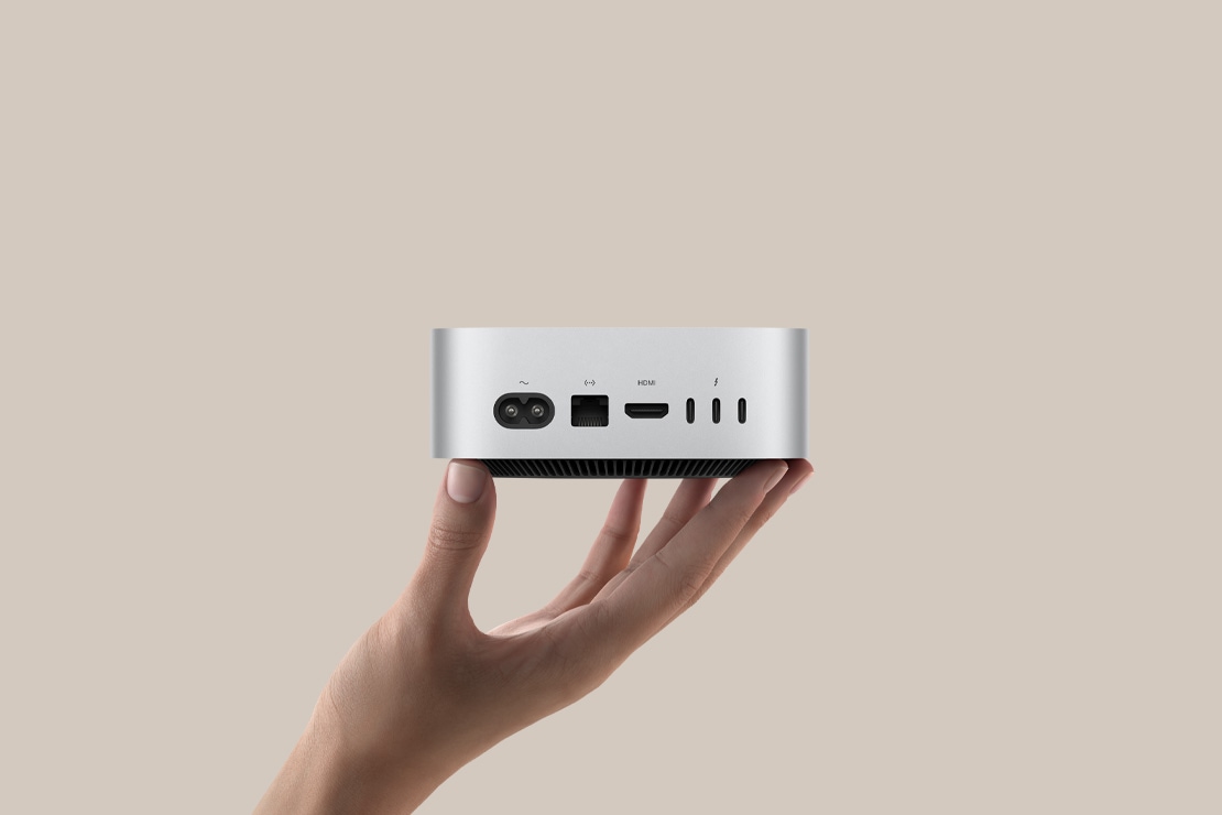 Користувач тримає Mac mini, демонструючи його порти на задній панелі