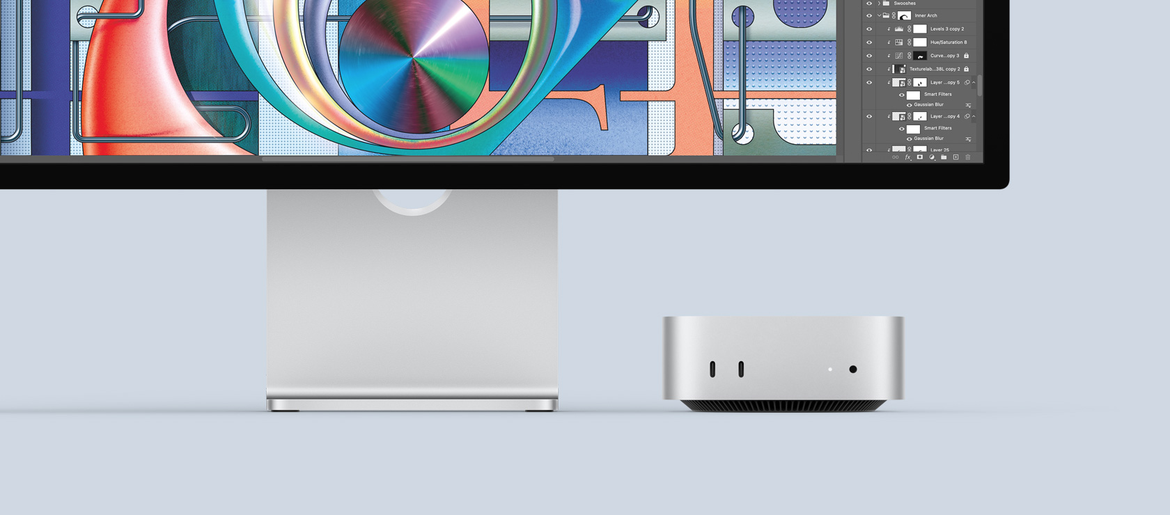 Вид спереду на сріблястий Mac mini, на передній панелі якого показано порти та світлодіодний індикатор. Його акуратно розташовано під монітором Mac, на екрані якого кольорове зображення
