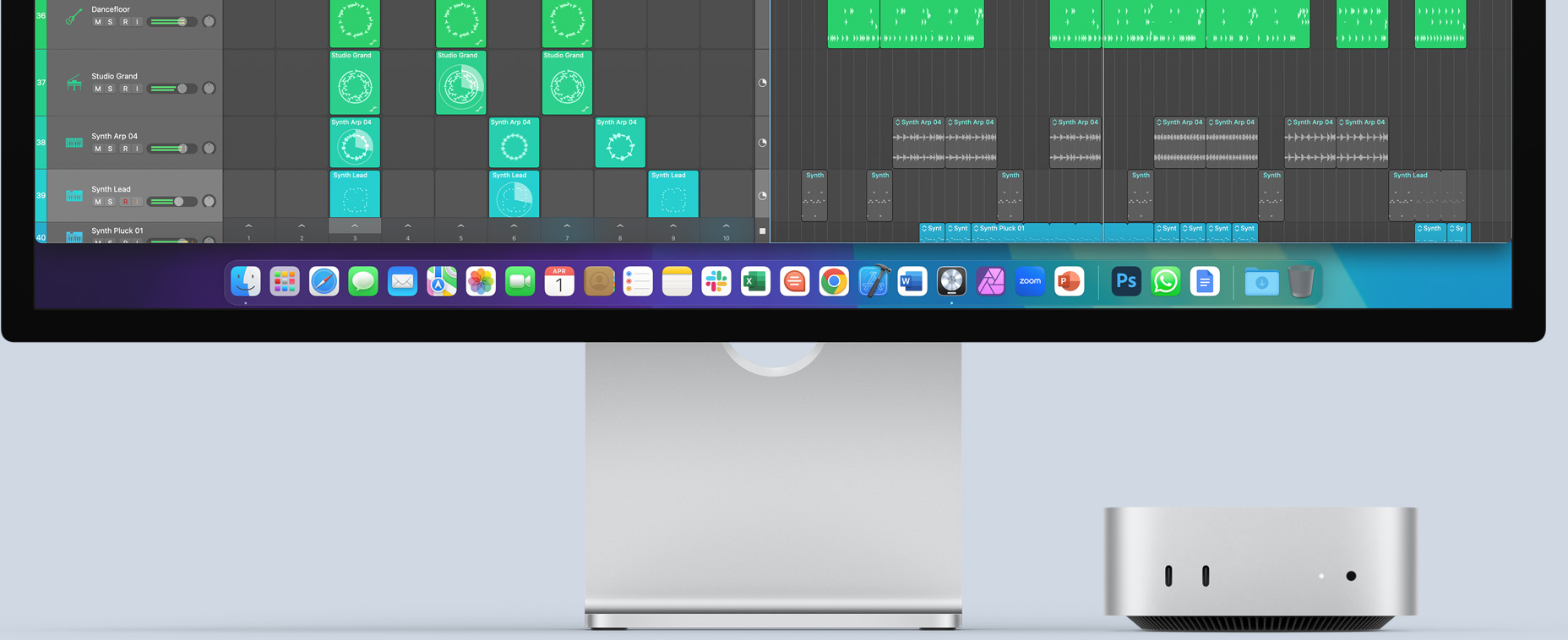 Вид спереду на сріблястий Mac mini, на передній панелі якого показано порти та світлодіодний індикатор. Він розташований під монітором Mac, на екрані якого відображається кольорове зображення й іконки додатків на панелі Dock