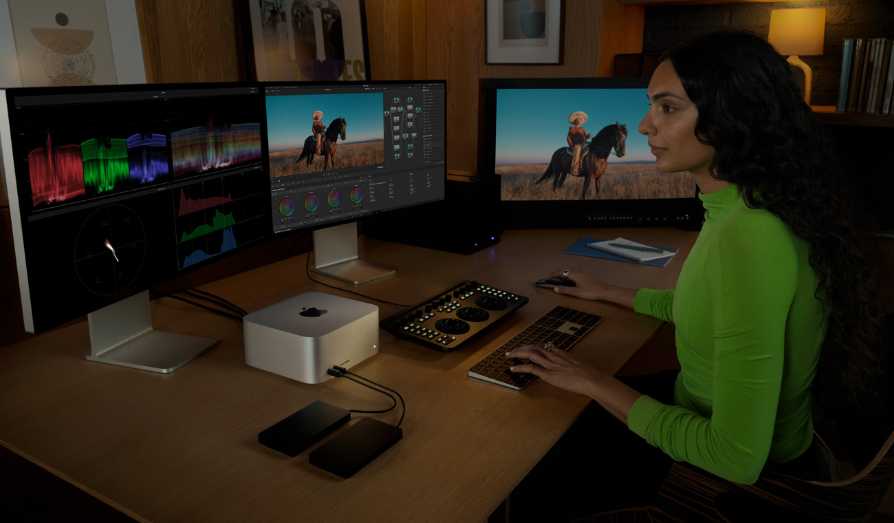 一位專業人士以 Mac Studio 連接三部顯示器進行檔案編輯